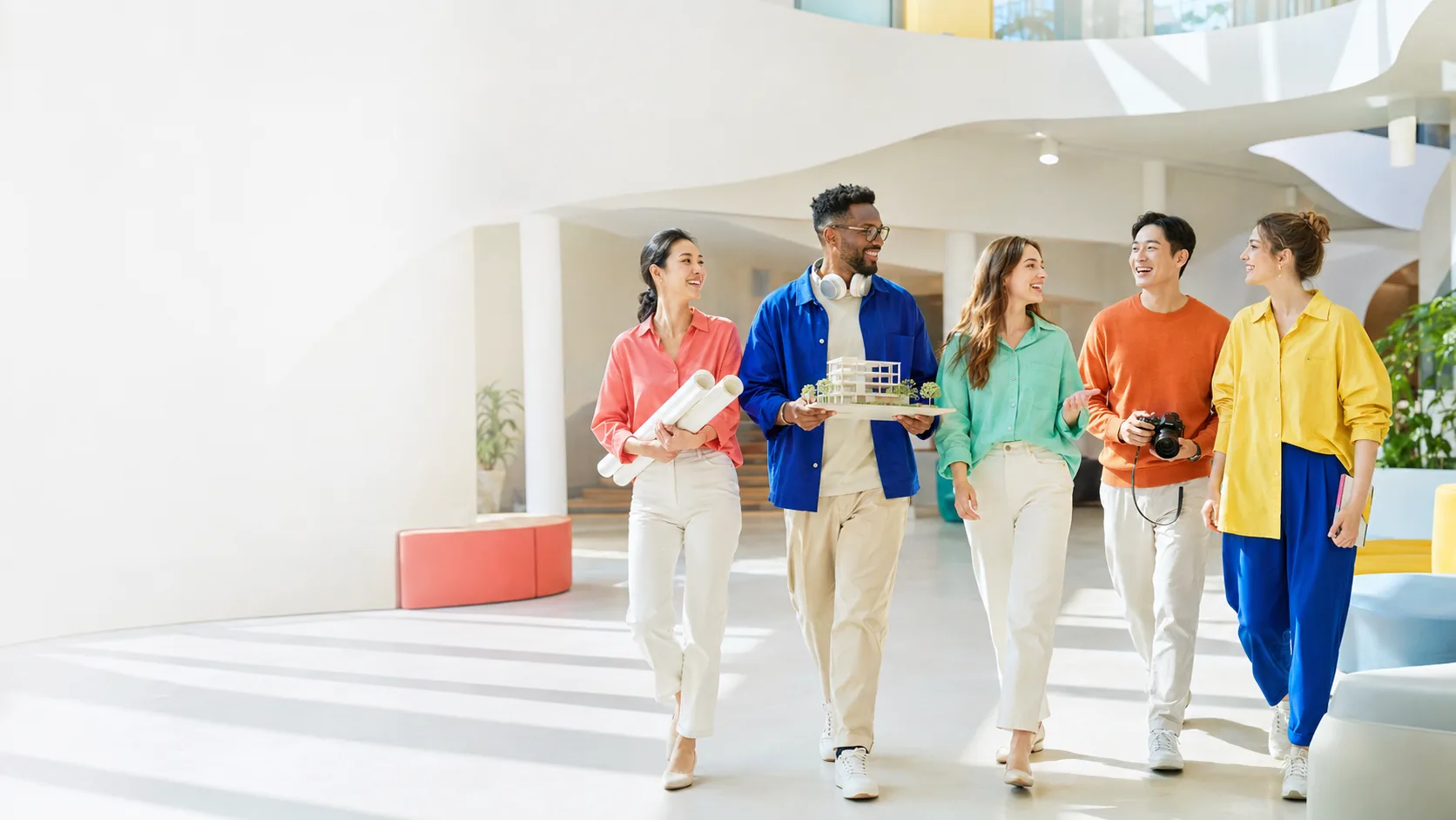 Collaborators walking together through a bright studio building
